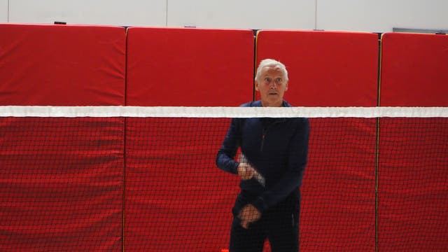 Jacques Duysens steht mit einem Badmintonschläger hinter einem Netz.