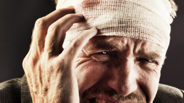 Ein Mann hält seinen verletzten Kopf und leidet