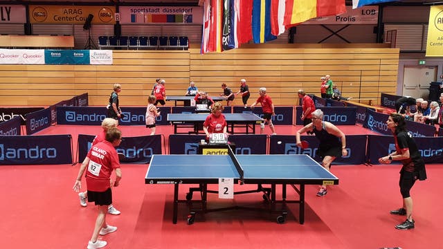 An mehreren Tischtennisplatten treten bei den PingPongParkinson German Open 2023 Spielerinnen und Spieler jeweils im Doppel gegeneinander an