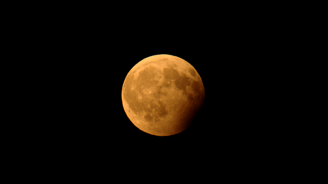 Foto des Mondes während einer partiellen Mondfinsternis, bei der ein Teil des Trabanten vom Kernschatten der Erde verdunkelt wird.