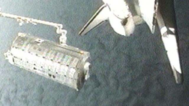 Das Japanese Pressurized Module am Greifarm der Raumfähre Discovery