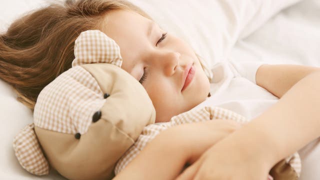 Schlafendes Mädchen im Bett mit Teddybär 