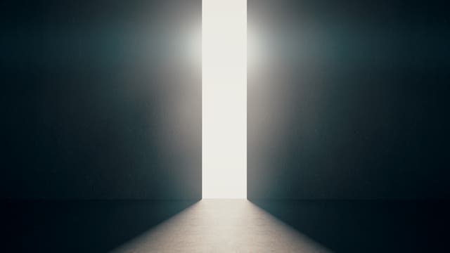 Gleißender Lichtschein dringt durch sich öffnenden Türspalt in dunklen Raum