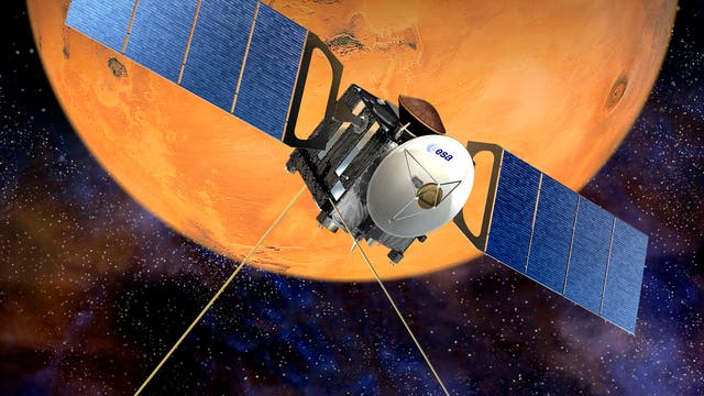 Eine Raumsonde mit großen blauen Solarpanelen schwebt im Weltraum vor dem Hintergrund des Planeten Mars. Auf der Sonde ist das Logo der ESA (Europäische Weltraumorganisation) sichtbar. Der Mars zeigt seine charakteristische rötliche Oberfläche mit Kratern und Tälern. Der Weltraum im Hintergrund ist dunkel mit vielen kleinen Sternen.