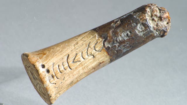 Im Bild zu sehen ist ein antiker Messergriff aus Elfenbein, in dem altindische Schriftzeichen eingeritzt sind. 