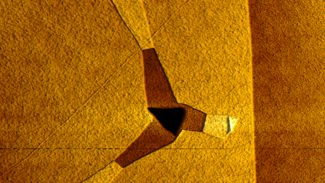 Das dreieckige Loch lässt drei sternförmig reißende Bänder in der Graphenschicht entstehen