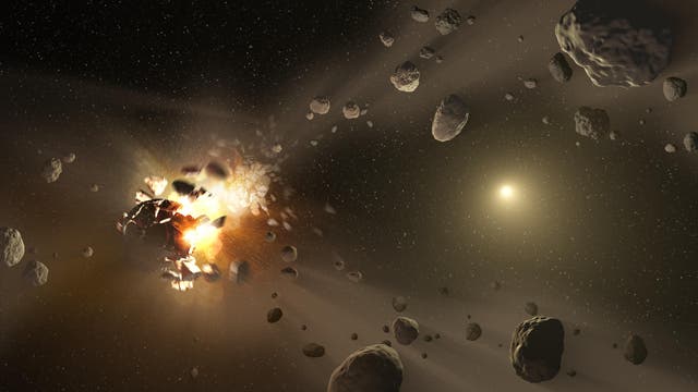 Eine künstlerische Darstellung einer Kollision im Asteroidengürtel im Weltraum. Zwei große Asteroiden prallen mit einem hellen Lichtblitz aufeinander, wobei Trümmerstücke in alle Richtungen fliegen. Im Hintergrund ist ein leuchtender Stern zu sehen, der die Szene beleuchtet. Die Umgebung ist voller kleinerer Asteroiden, die durch den Raum schweben.