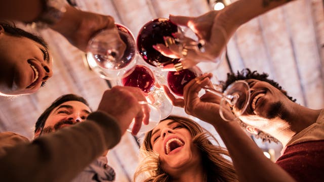 Eine bunt gemischte Gruppe trinkt fröhlich Rotwein