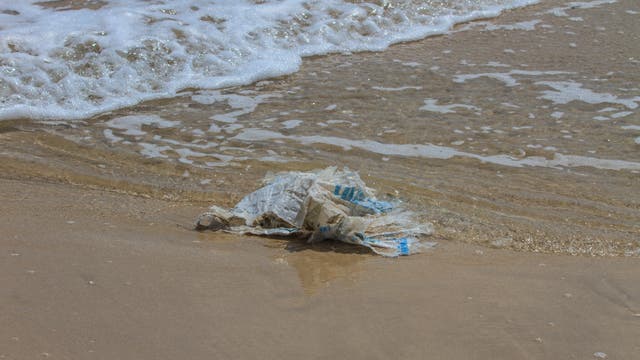 Eine Plastiktüte verschmutzt den Strand und belastet das Meer