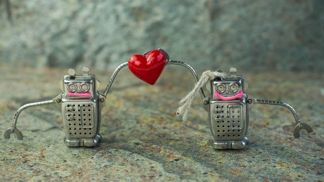 Zwei Blechroboter halten ein Herz hoch