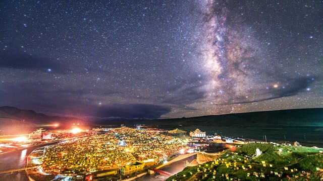 Das Band der Milchstraße leuchtet über der Siedlung Yarchen Gar im Hochland von Tibet. Hier, in 4000 Meter Höhe, leben und beten mehr als 10 000 buddhistische Mönche und Nonnen unter einfachen Verhältnissen in ihren kleinen Meditationshütten. 