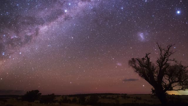 Die Milchstraße, die beiden Magellanschen Wolken und der Stern Canopus leuchten über den Weiten des australischen Outback.