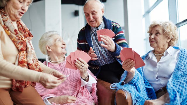 Seniorinnen spielen mit altem Herrn Karten