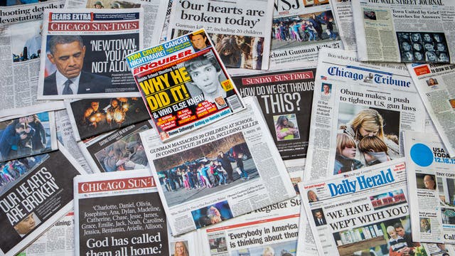 Zeitungen, deren Schlagzeilen sich mit Terror befassen, liegen ausgebreitet auf dem Boden.