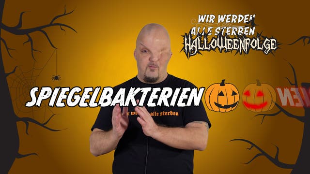 Eine Person steht vor einem orangefarbenen Hintergrund mit Halloween-Motiven wie Spinnweben und Kürbissen. Der Text „Spiegelbakterien“ ist in großen Buchstaben über das Bild gelegt. Oben rechts steht „Wir werden alle sterben Halloweenfolge“ in stilisierter Schrift. Die Person trägt ein schwarzes T-Shirt mit einem nicht vollständig lesbaren Text.