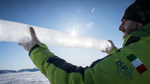 Ein Forscher hält einen Eisbohrkern in die Kamera