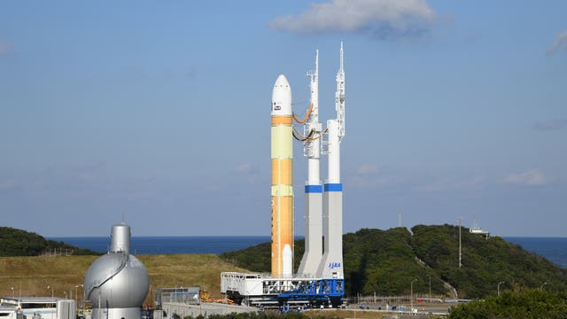 Eine gelbe Rakete auf einer Startplattform rollt durch die Landschaft.