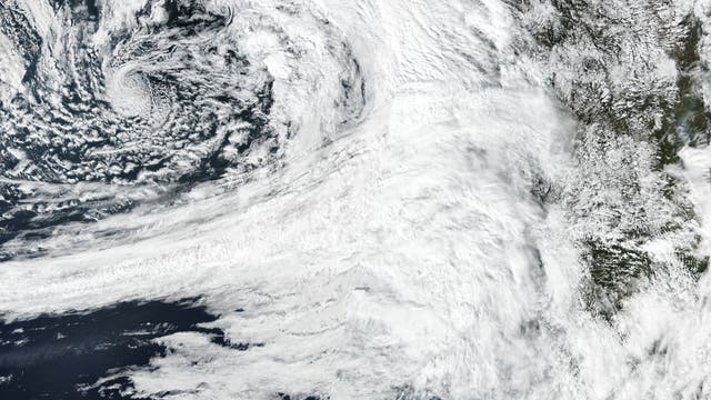 Ein starkes Wolkenband in Weiß auf dem Satellitenbild reicht vom dunkelblauen Pazifik bis an die Küste Nordamerikas. Der Kontinent ist am rechten Bildrand in Grün- und Brauntönen zu erkennen.