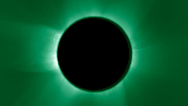 Eine totale Sonnenfinsternis mit einem schwarzen Kreis in der Mitte, der die Sonne verdeckt. Um den Kreis herum ist die grüne Korona der Sonne sichtbar, die in alle Richtungen strahlt. Die Aufnahme zeigt die beeindruckende Struktur und Leuchtkraft der Sonnenkorona während der künstlich erzeugten Finsternis.