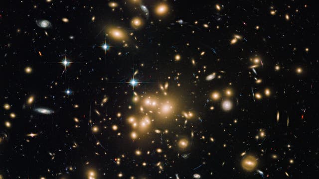 Der Galaxienhaufen Abell 1689 wird von Astronomen als Gravitationslinse genutzt, mit der sie extrem weit entfernte Galaxien ausmachen können. Der Linseneffekt deutet das Vorhandensein Dunkler Materie an.