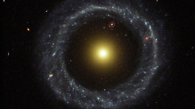 Eine rötliche Galaxie mit einem großen hellen Ring außenrum