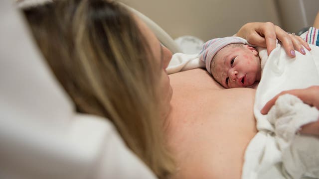 Ein Neugeborenes liegt im Arm der Mutter