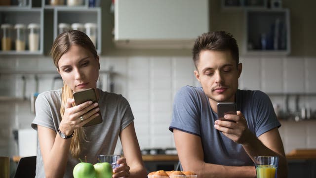 Mann und Frau, vertieft in ihre Handys