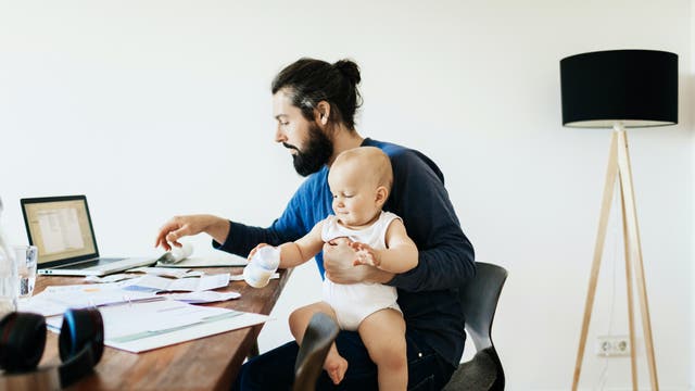 Hipper Papa beim Arbeiten mit Baby auf dem Schoß