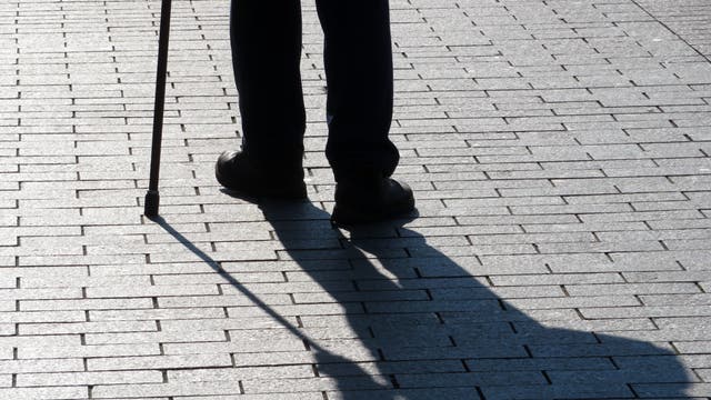 Silhouette und Schatten der Beine eines alten Mannes, der am Stock geht