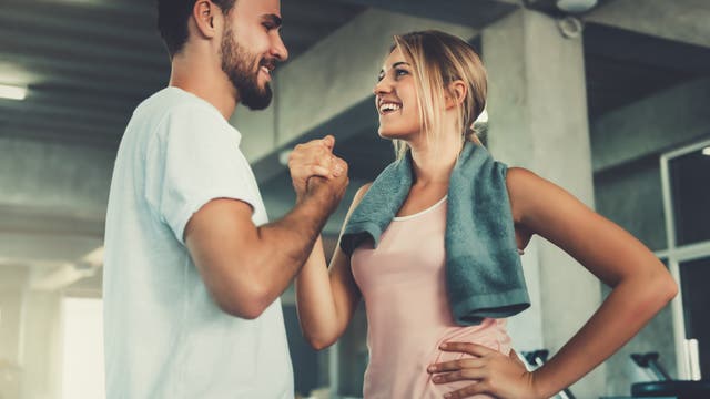 Eine Frau und ein Mann in Sportkleidung geben sich einen Handschlag und freuen sich.