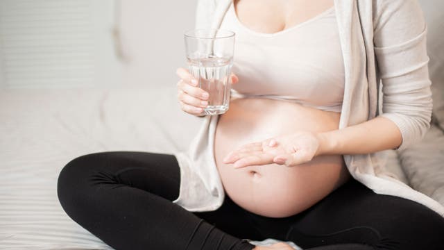 Eine schwangere Frau nimmt eine Tablette