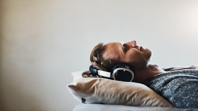 Mann hört Musik im Bett