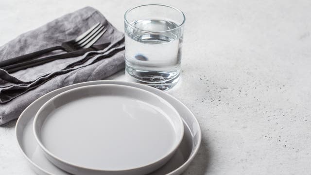 Ein leerer Teller und ein Glas Wasser stehen auf einem Tisch