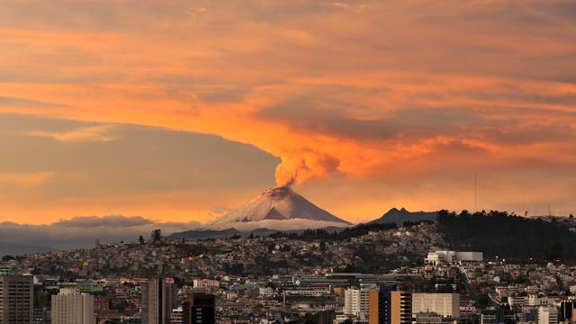 Ausbruch des Vulkans Cotopaxi nahe der Stadt Quito. Im Vordergrund das Stadtzentrum, im Hintergrund ein rauchender Vulkankegel.