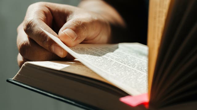 Großaufnahme einer geöffneten Bibel, die in den Händen gehalten wird.