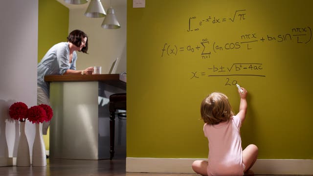 Ein Kleinkind schreibt mathematische Formeln auf die Tapete.