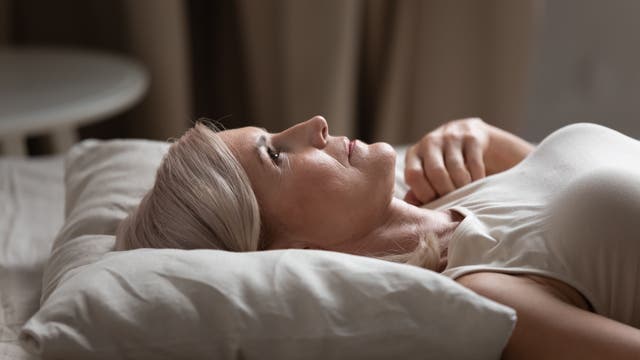 Eine Frau mittleren Alters liegt wach im Bett