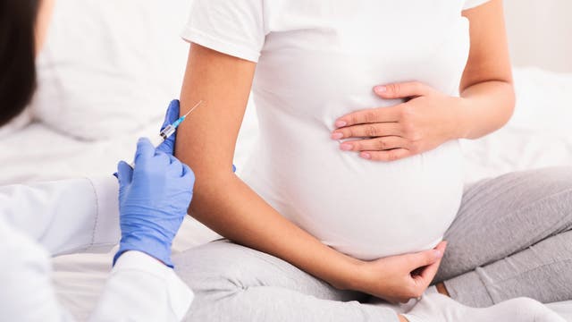 Eine schwangere Frau bekommt eine Spritze in den Arm.