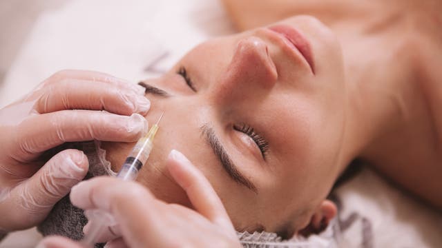 Frau bekommt Botox in Stirn gespritzt
