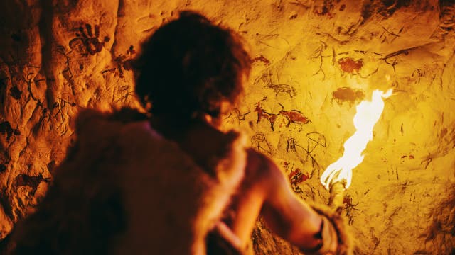 Ein steinzeitlicher Jäger betrachtet Höhlenmalereien (Illustration)