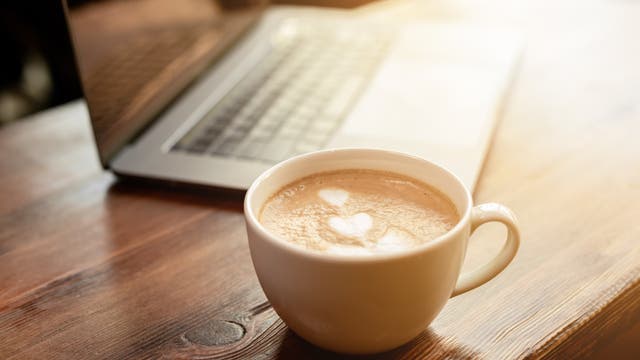 Ein Milchkaffee steht vor einem Laptop