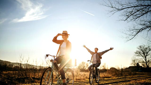 Freunde fahren Rad auf einem Feldweg in der Abendsonne