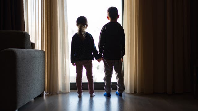 Mädchen und Junge im Gegenlicht vor einer gläsernen Tür