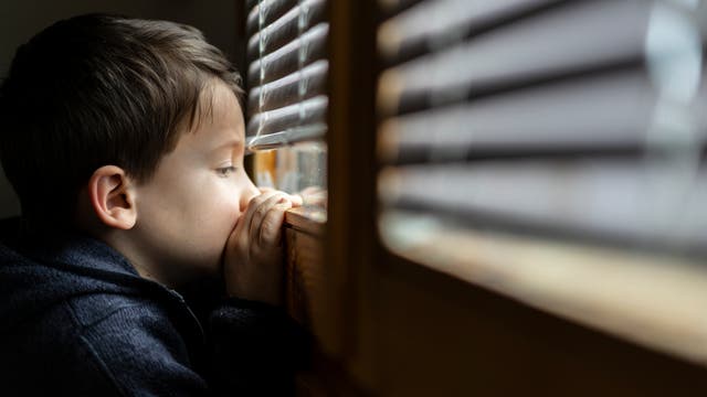 Ein Junge blickt niedergeschlagen aus dem Fenster.