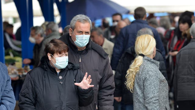 Ein Mann und eine Frau mit Mund-Nase-Schutz auf einer belebten Straße.