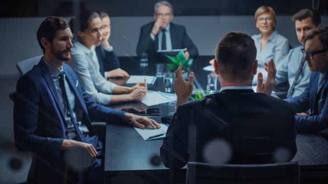 Eine Gruppe Geschäftsleute sitzt in einem Meeting zusammen