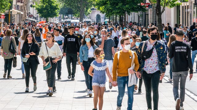Eine Menschenmenge in einer Einkaufsstraße, zum Teil mit, zum Teil ohne Maske. Aufgenommen in Frankreich nach dem Ende des Lockdowns.