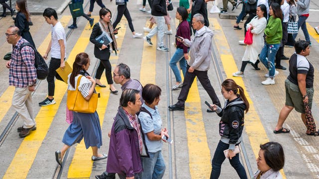 Menschen überqueren eine Straße in Hongkong.