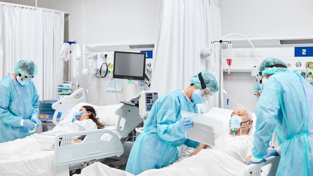 Ein älterer Patient und eine jüngere Patientin mit MNS in Intensivbetten, umgeben von Ärztinnen und Ärzten in Schutzausrüstung.
