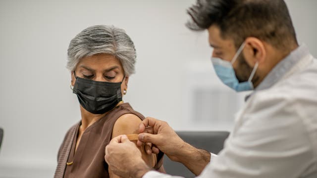 Eine Frau erhält nach der Impfung ein Pflaster auf die Einstichstelle.